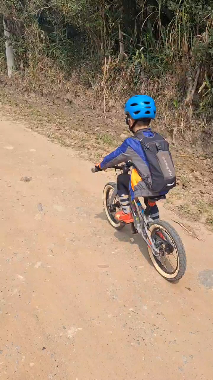 Criança pedalando em estrada de terra