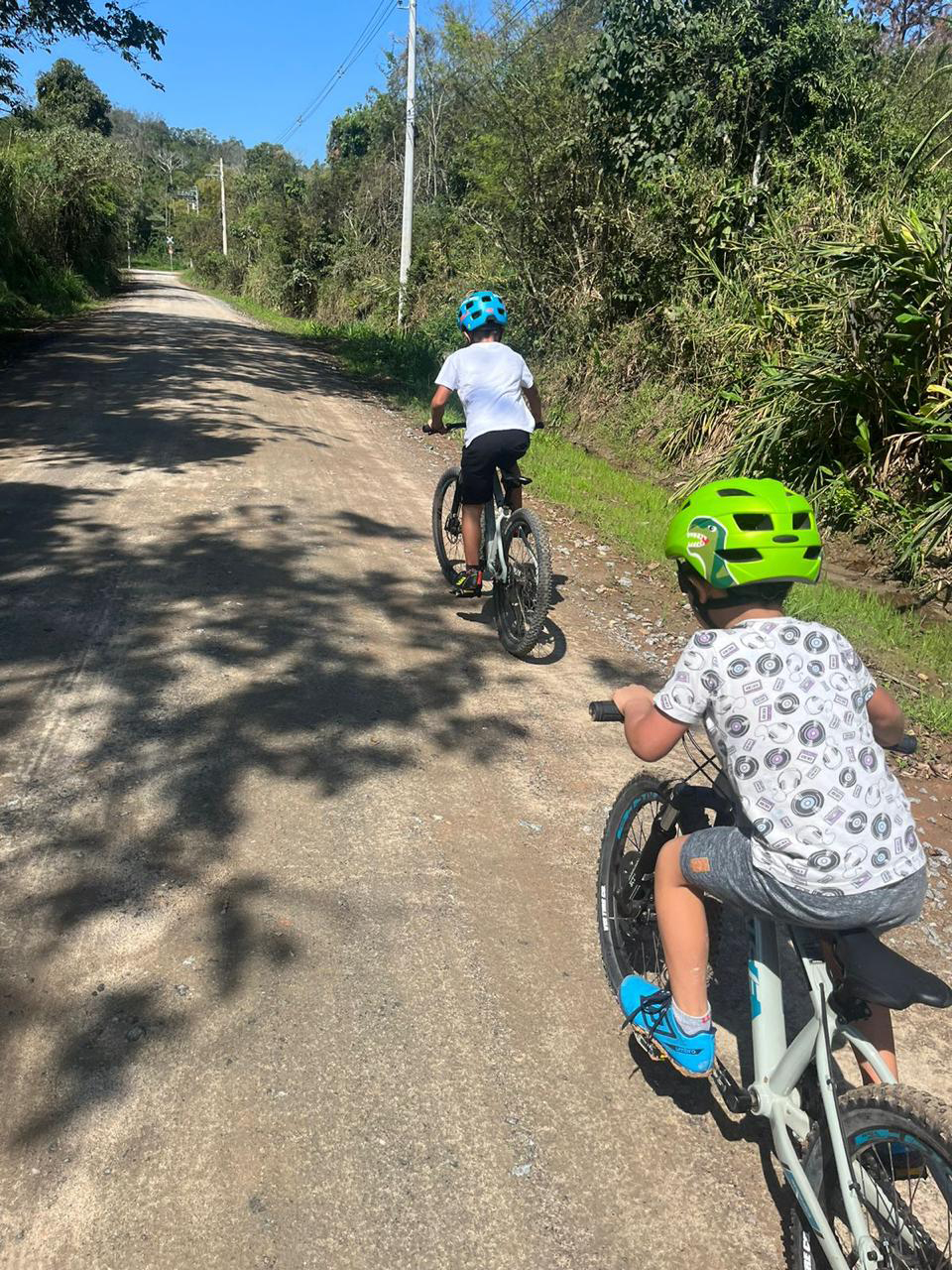 Crianças pedalando juntas em estrada de terra